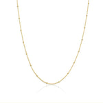 A gold satellite chain necklace laid out on a plain background.