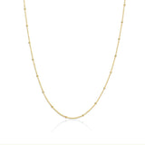 A gold satellite chain necklace laid out on a plain background.