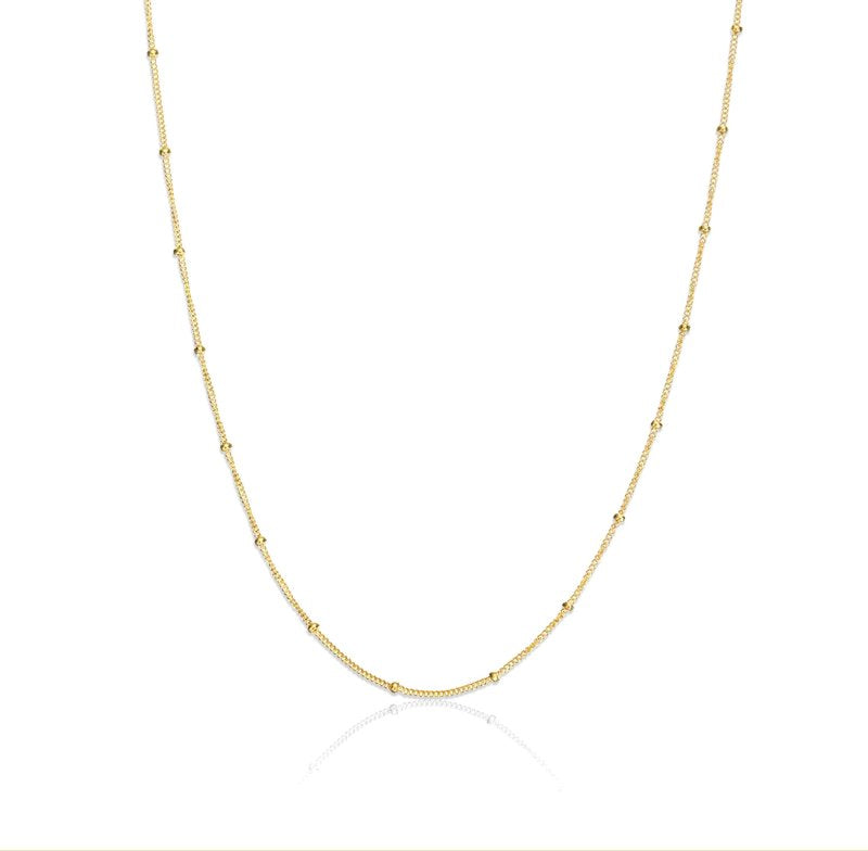 A gold satellite chain necklace laid out on a plain background.