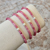 Three pink beaded bracelets on a beige stand with a neutral background
