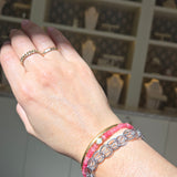 Hand wearing a pink bracelet with a blurred background