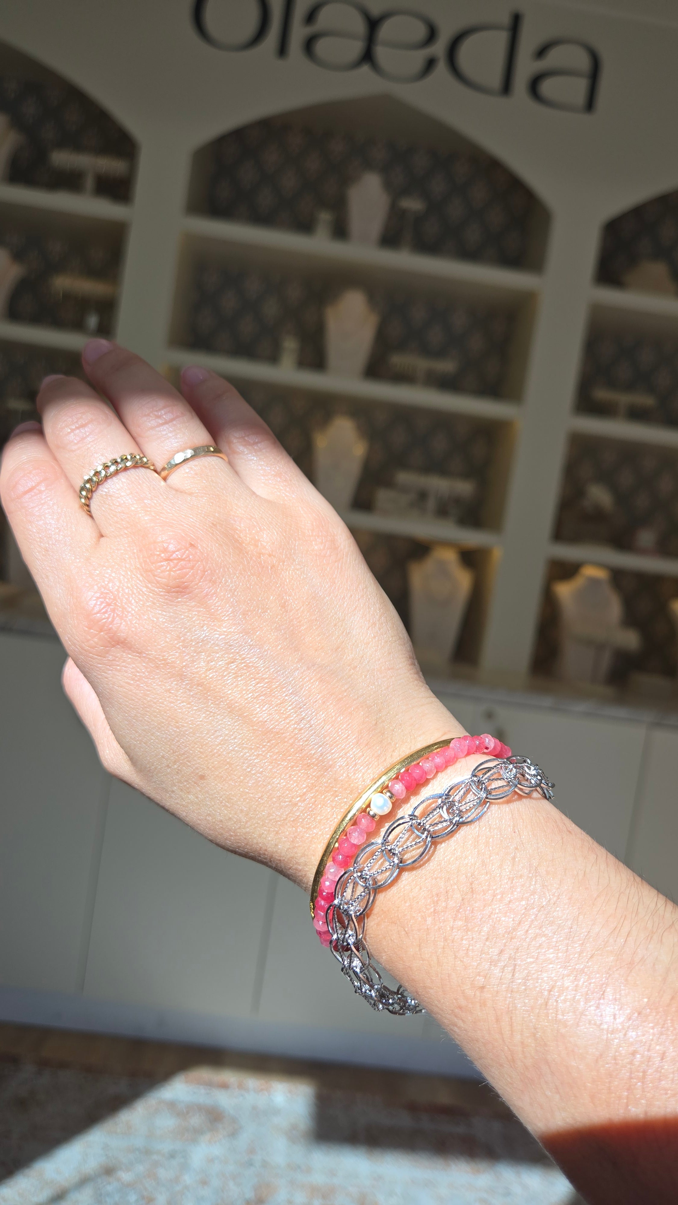 Hand wearing a pink bracelet with a blurred background