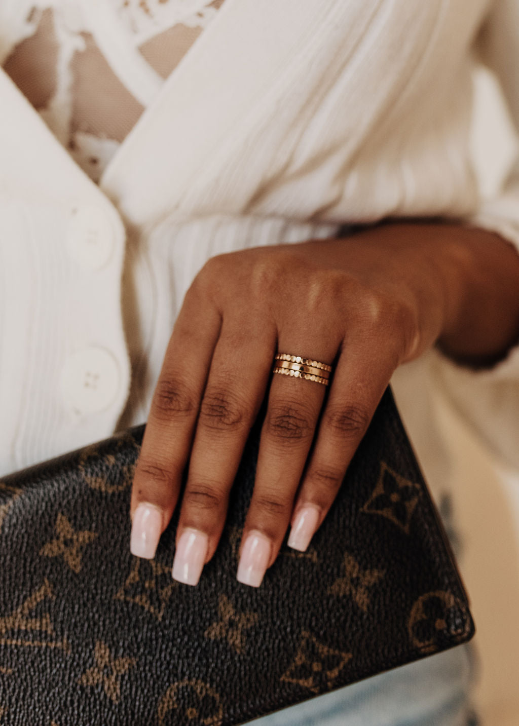 Hand with a gold ring holding a patterned clutch