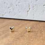 Small gold earrings on a textured surface