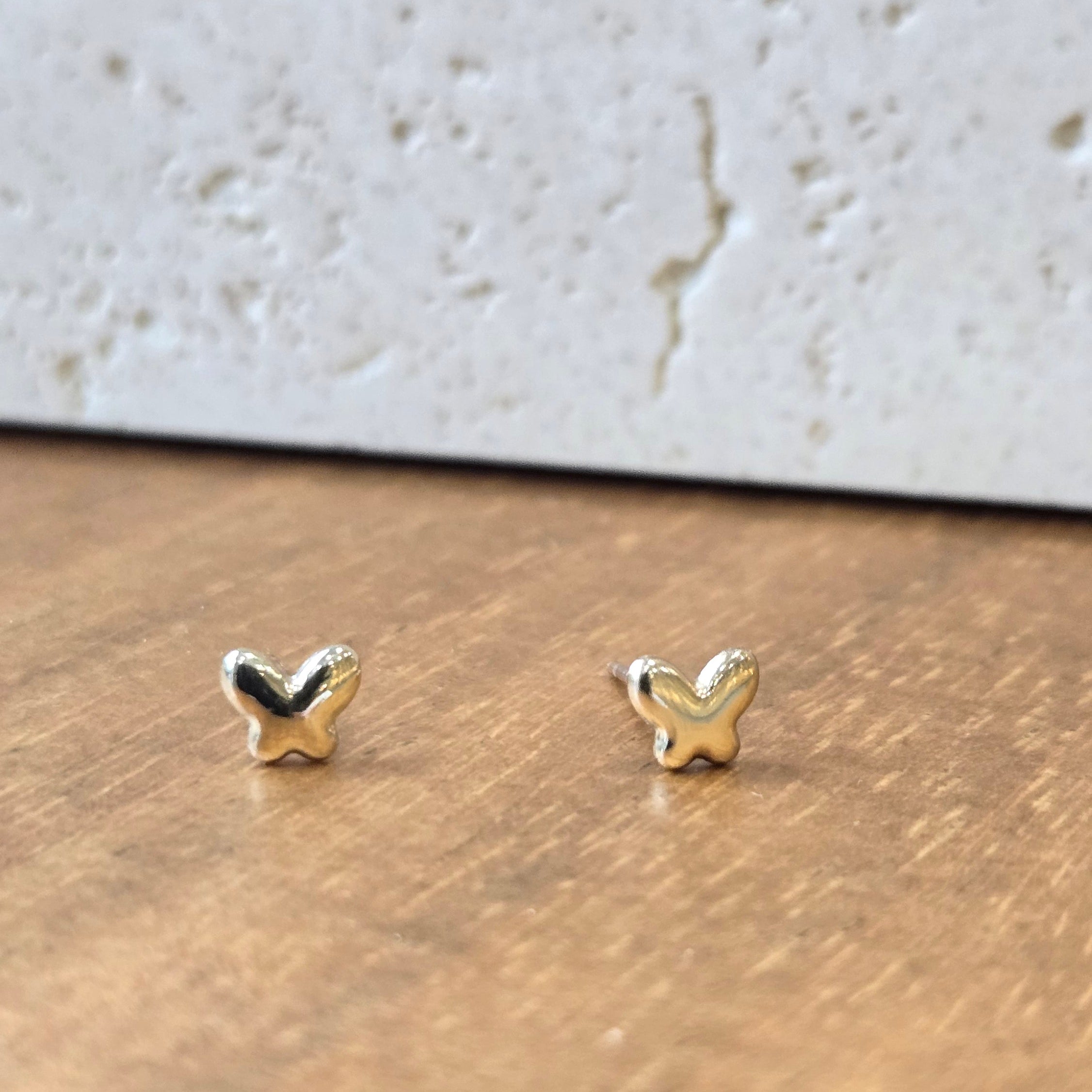 Small gold earrings on a textured surface