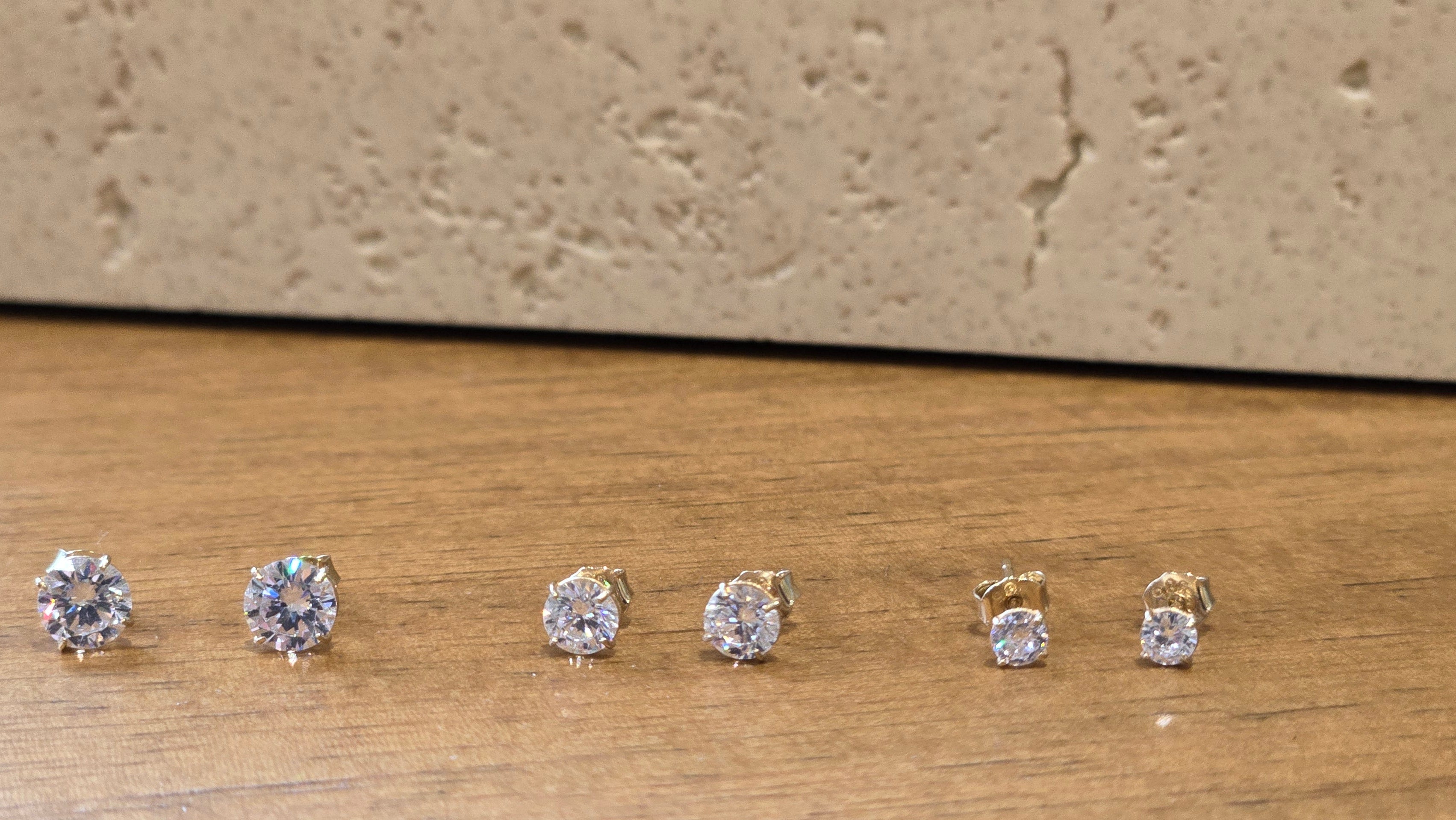 Set of diamond stud earrings on a wooden surface