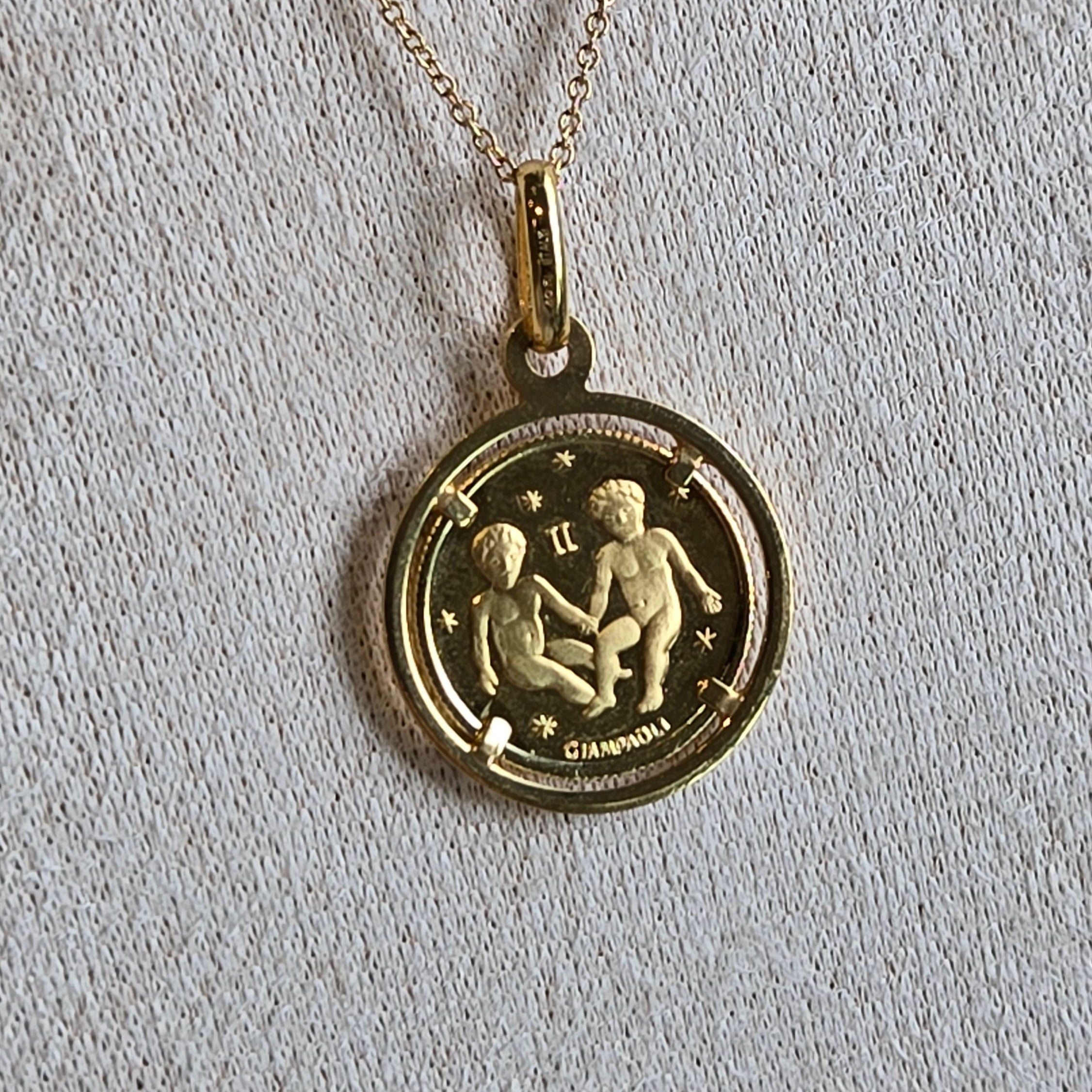 Gold necklace with a round pendant featuring an astrological symbol on a light gray background