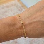 Gold bracelet on a wrist with a neutral background