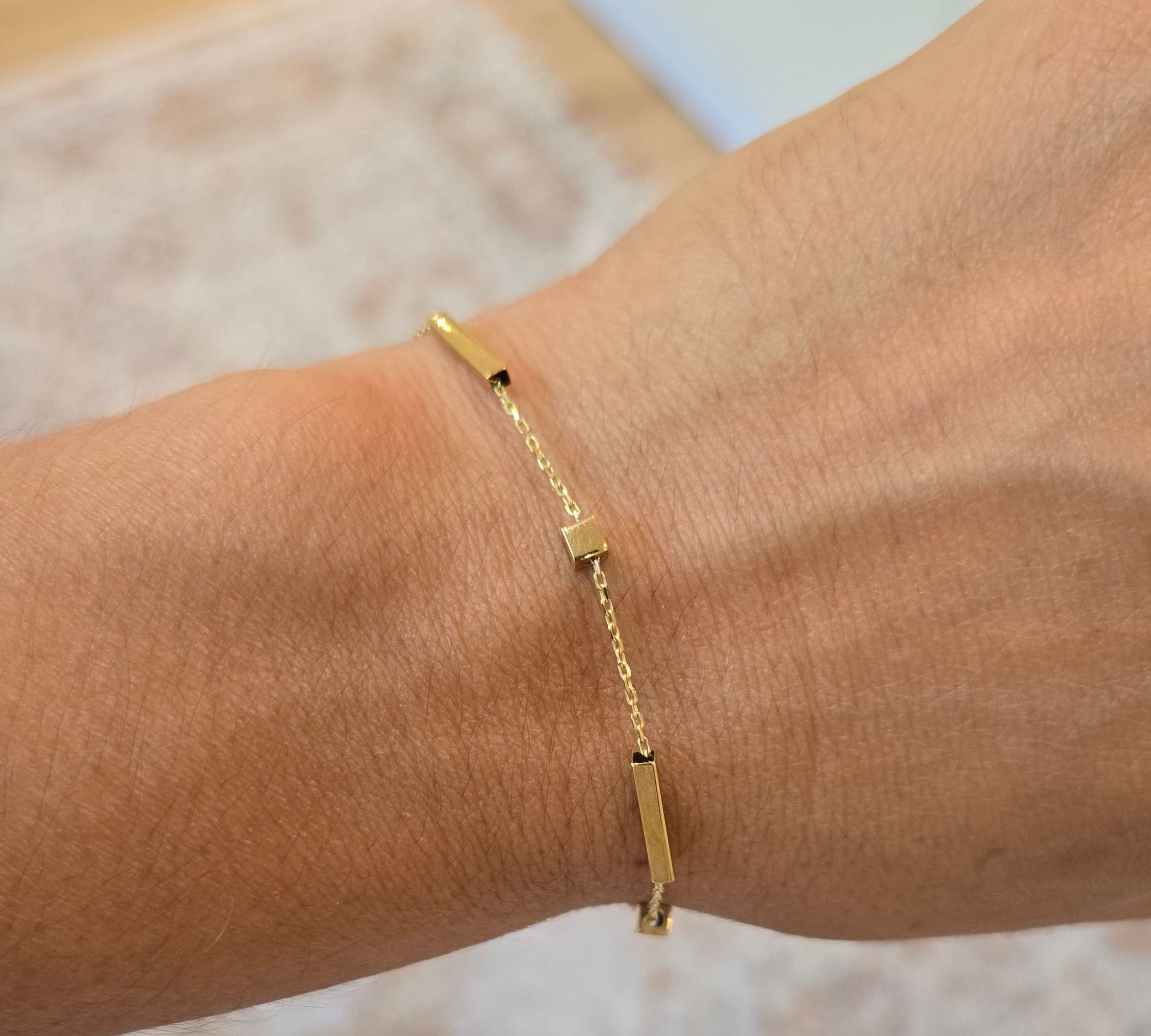 Gold bracelet on a wrist with a neutral background
