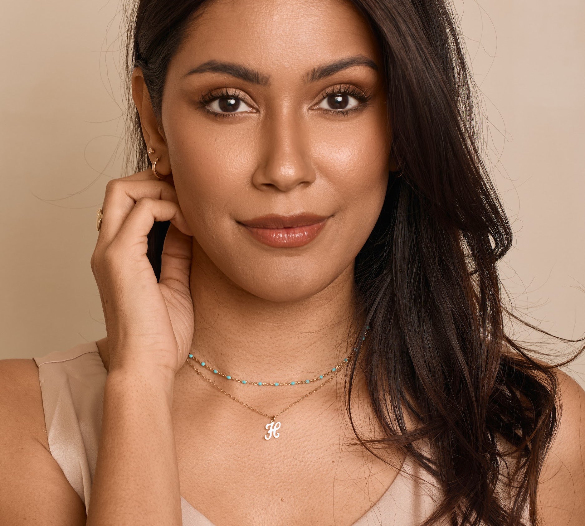Woman wearing a necklace with a beige background