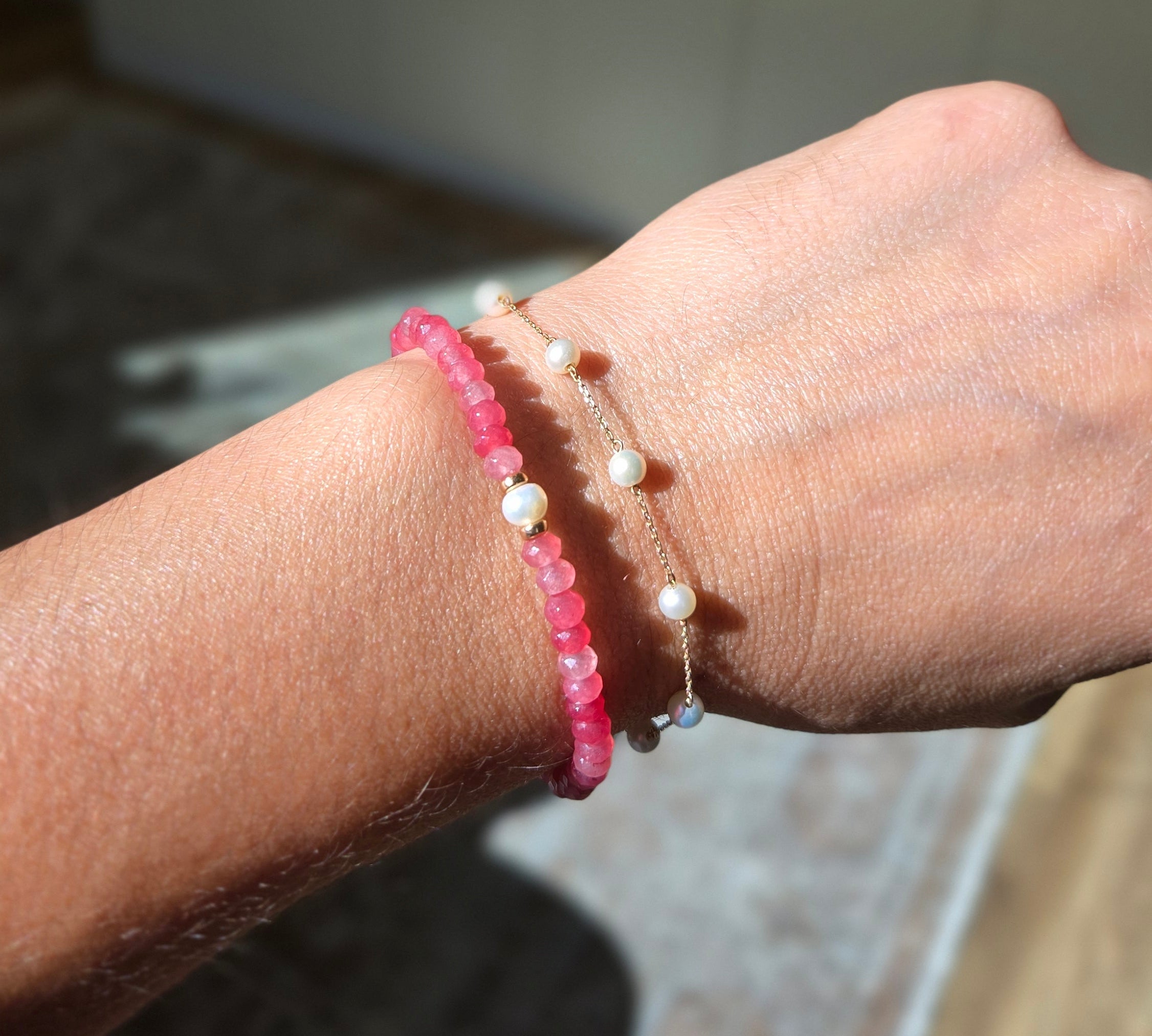 Close-up of a wrist wearing two bracelets with a blurred background