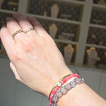 Hand wearing a pink bracelet with a blurred background